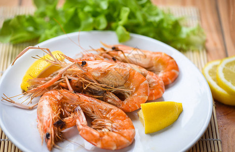 白盘餐桌上的虾烤烧海鲜虾用柠檬和蔬菜沙图片