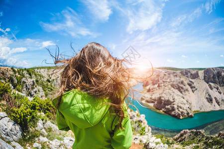 一个长发随风生长的女孩站在峡谷的边缘克尔卡公园峡谷底部的河流拐弯处一名妇女前往克罗地亚风图片