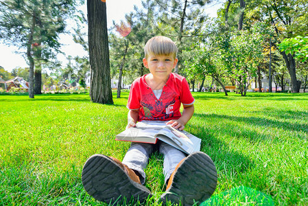 一个穿红衣服的男孩手里拿着一本书坐在图片