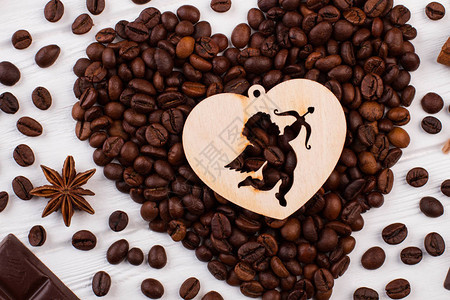 心形咖啡豆和胶合板心与丘比特烤咖啡豆在白色木制背景上形成心图片