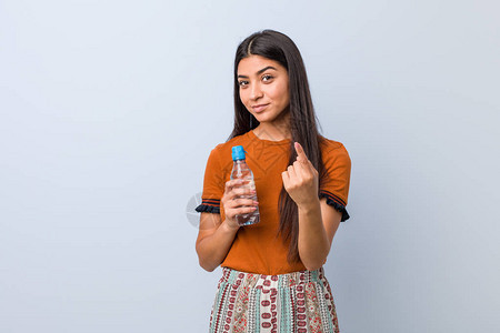 拿着水瓶的阿拉伯年轻女人用手指着你好像邀请者靠近了一样图片