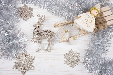 在木制圣诞雪橇玩具驯鹿银和白木背景的雪花上白色与白隔图片