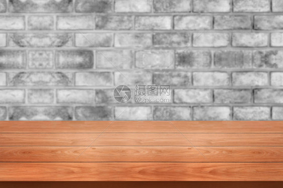 生锈砖墙前面的木板桌模糊了背景图片