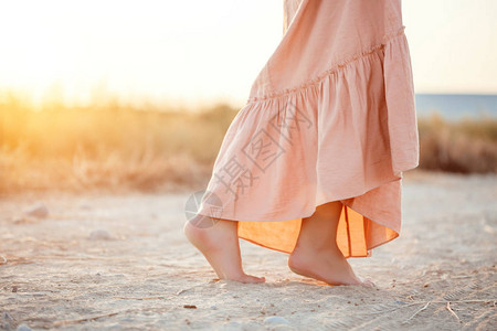 街头行走,脚步在日落时在沙滩上行走穿着粉红背景