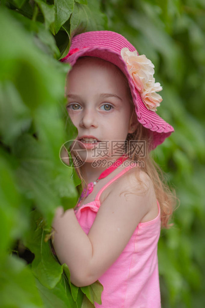 在游泳池附近休息的小女孩一个4岁的女孩在新鲜空气中休息夏天戴粉色帽子和粉色衣服的女孩小女孩脖子上有花图片