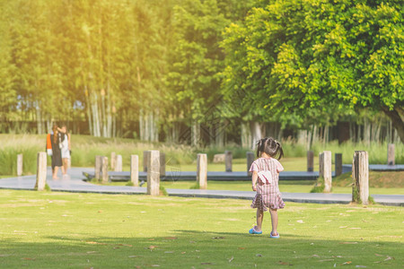 一个穿粉红色裙子的小女孩晚上在公园的绿草坪上玩耍享受图片