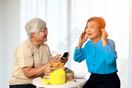 两个亚洲70岁老人在客厅用白窗帘一起享受活动图片