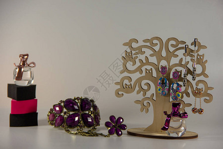 长耳环的树形木板手掌上的紫色手镯小瓶女香水白底面朝海绵等形背景图片
