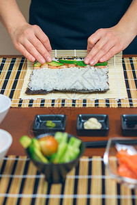 女厨师用米饭鳄梨和虾在挪威海藻上滚图片