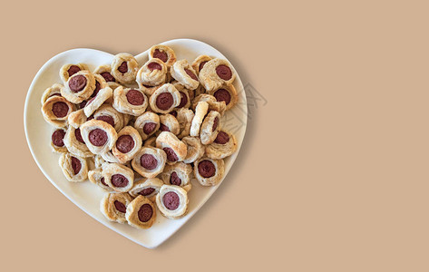 糕点和迷你热狗在心脏形状的盘子在木图片