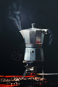 黑色背景中的摩卡壶旧咖啡机和咖啡豆图片