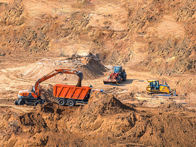 挖掘机装载机在施工现场装载自卸车停在沙坑的挖掘机和轮式装载机图片