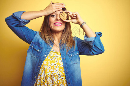 年轻美女在黄色背景下吃巧克力薯片饼干图片