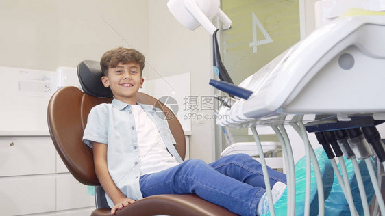 可爱的小男孩坐在牙科椅上等待牙齿检查图片