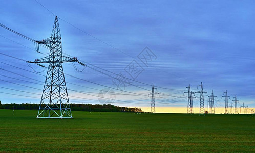 日落地平线蓝天背景下农田输电线路桅杆和支架背景图片