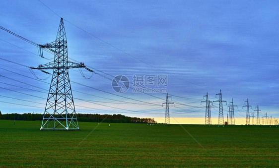 日落地平线蓝天背景下农田输电线路桅杆和支架图片