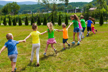 儿童在绿草坪上玩牵手游戏儿童排队跑来图片