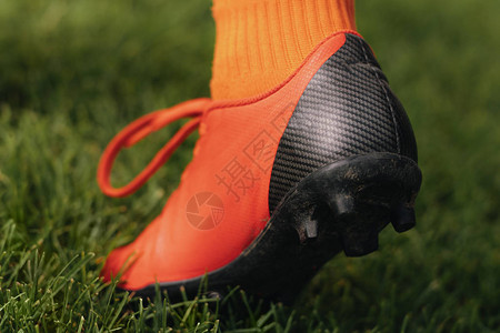 绿色草坪背景上的特写螺柱鞋在草地上的足球夹板足球员在足球鞋中迈出一步详图片