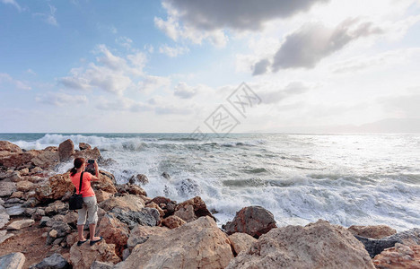 有吸引力的成熟旅行者女使用手机拍摄美丽的海景照片复制空间您图片