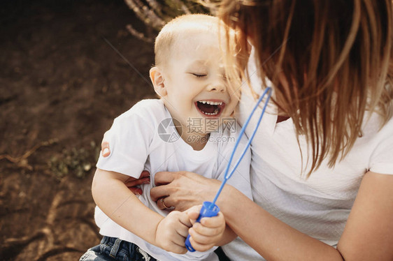 一个可爱的孩子在他母亲的怀里笑的上镜头当他的母亲在外面给他挠痒时图片