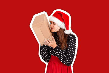 戴着圣诞帽的失望女孩手里拿着一份大礼物具有时尚色彩背景的杂志拼贴风图片