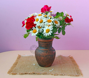 陶罐中的白雏菊和红玫瑰花束正在被解职淡紫色背景上的花盆里的花桌子上花瓶里的洋背景图片