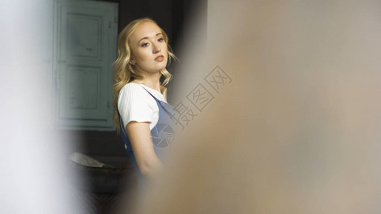 金发美女穿着白色T恤和蓝衬衣站在客厅图片