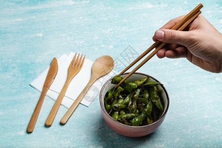 蓝色桌面上的熟毛豆小吃豆荚图片