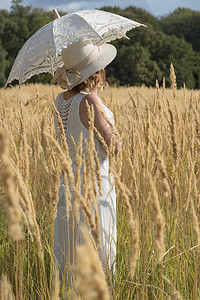 年轻女孩在长高黄尖甲的田地上在一图片