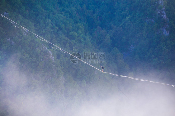 一个人沿着高在云层上方的拉长吊索行走highliner在峡谷中通过长而高的吊索拉力来保持平衡波斯尼亚和黑萨哥维那图片