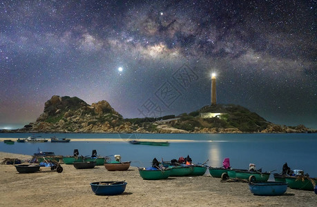 海边渔村的夜景紧靠着灯塔的夜景在天空中闪耀光芒图片