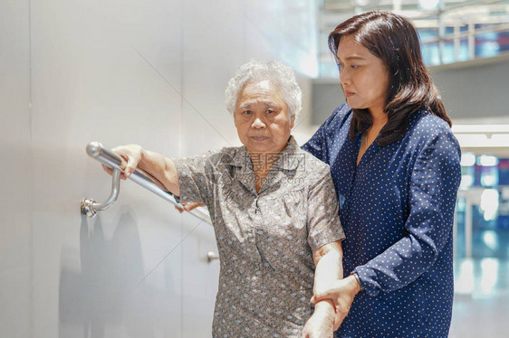 亚洲老年或老年妇人患者在护理医院病房使用斜坡走道把手安全与帮助支持助理图片