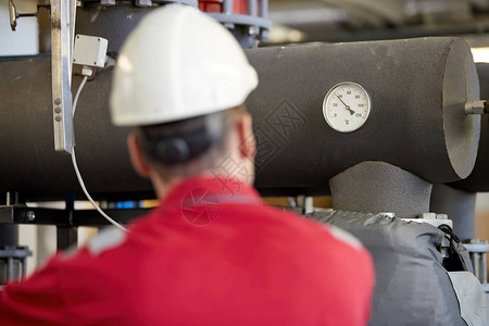 能源行业一名身着红色工作服和白色头盔的技术人员正在检查加热参数采暖配水技术电力行图片