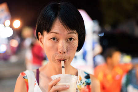 亚裔女在夜市上喝着著名的图片