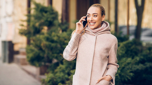 快乐的笑女人在城市户外用手机聊天秋天图片