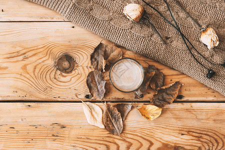 秋天的背景咖啡秋叶和针织毛衣一杯咖啡和针织围巾木制的桌子上喝咖啡图片