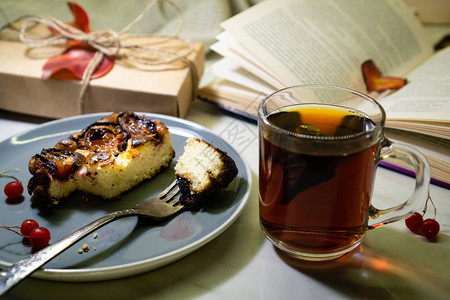 前景是芝士蛋糕和叉子一杯茶和红色荚果图片