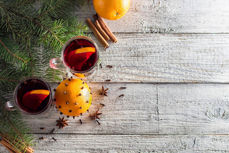 圣诞节热辣味葡萄酒含肉桂橙和有树的白木图片