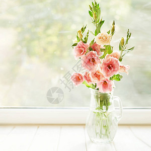 以窗户为背景的桌子上放着洋桔梗花的瓶图片