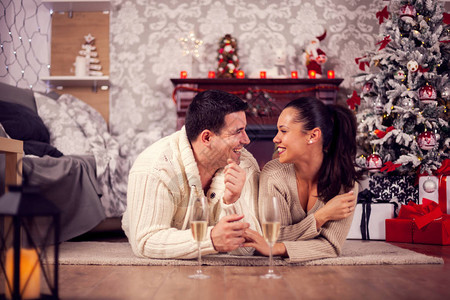 年轻丈夫和妻子在圣诞节的客厅里躺着一对图片