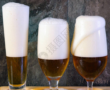 将啤酒倒入黑色石板吧台上的传统啤酒杯中图片