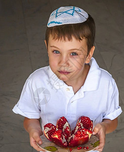 可爱的白人犹太男孩头顶上戴着一块石榴水果盘图片