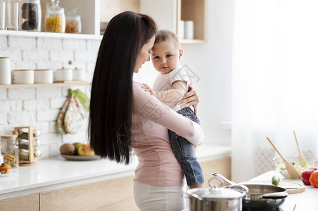 年轻母亲与小儿子亲近在厨房准备婴图片