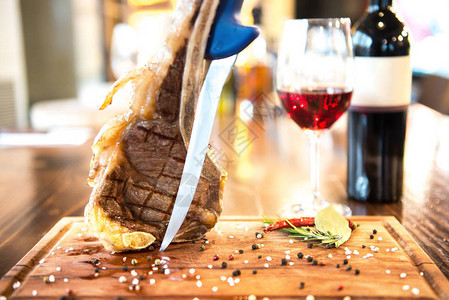 木板上烤美味可口的垂直羊排和一杯葡萄酒和瓶子图片