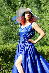 一位身穿蓝色连衣裙戴着华丽的雪白帽子的女士图片