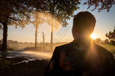 日落时浇灌玉米田的农业灌溉系统剪影使用中心枢轴喷水系统灌溉玉米田荷图片