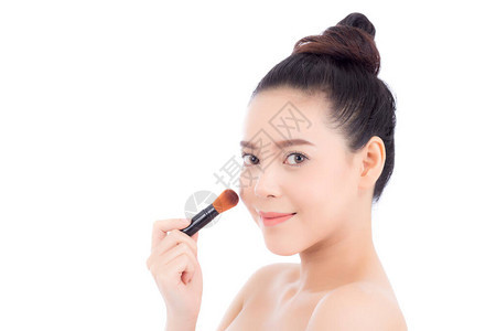 肖像美容的亚裔女申请用白色背景上孤立的脸颊刷子来补妆图片