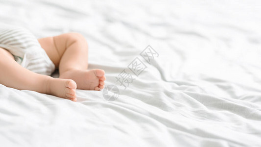紧躺在床上的婴儿小腿穿着体衣用复制空图片