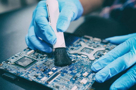 亚洲技术员用刷子修理和清洁脏尘微电路主板计算机电子技术图片