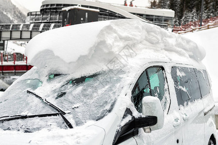 汽车在大雪后覆盖着厚的雪层的街道上极端暴风雪后果车辆挡风玻璃与冻图片